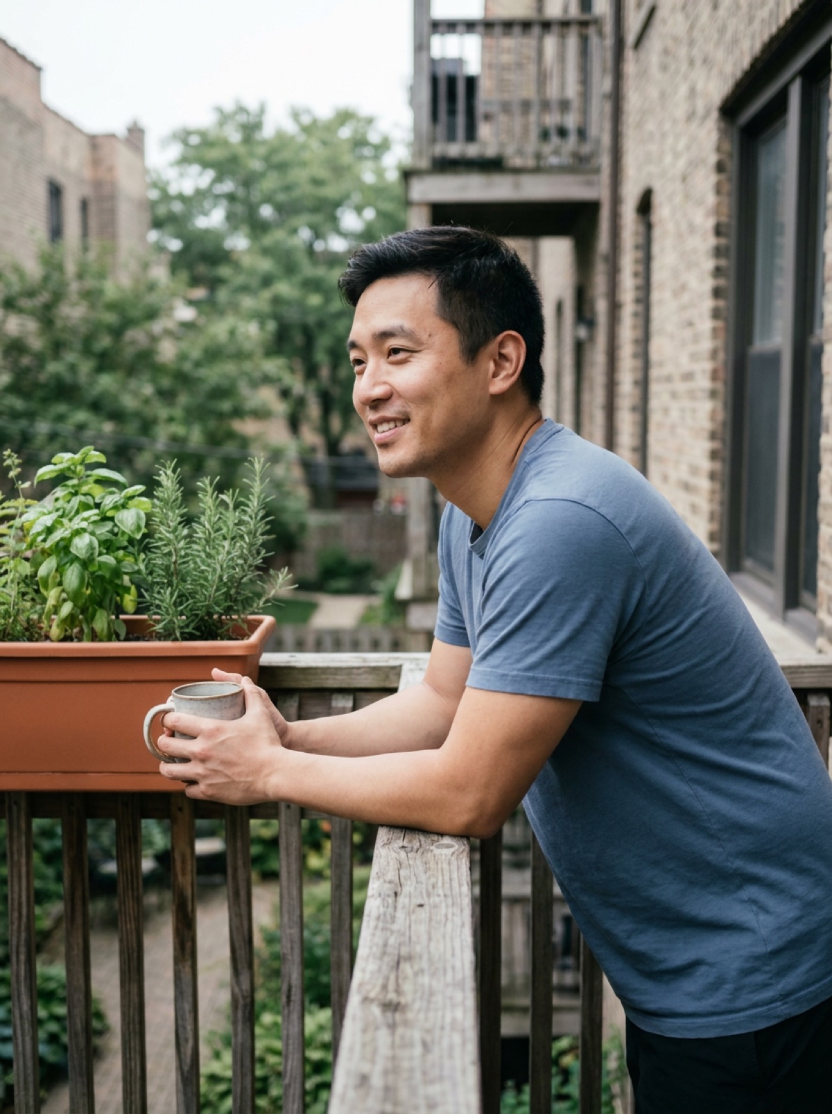 A man in his thirties on his apartment balcony with a coffee, looking toward the courtyard